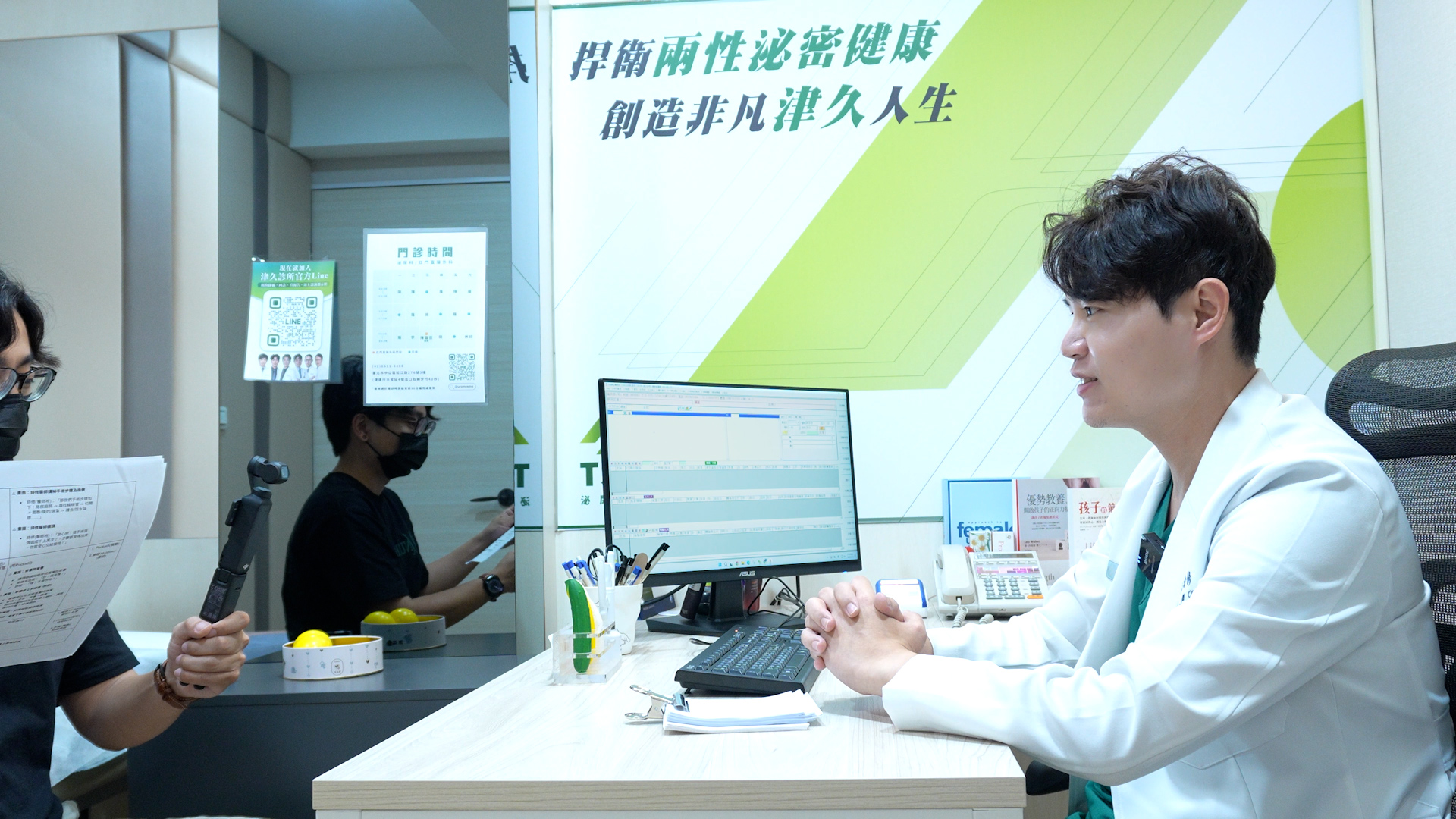 津久診所醫師於診間接受採訪,背景「捍衛兩性泌密健康 創造非凡津久人生」品牌標語