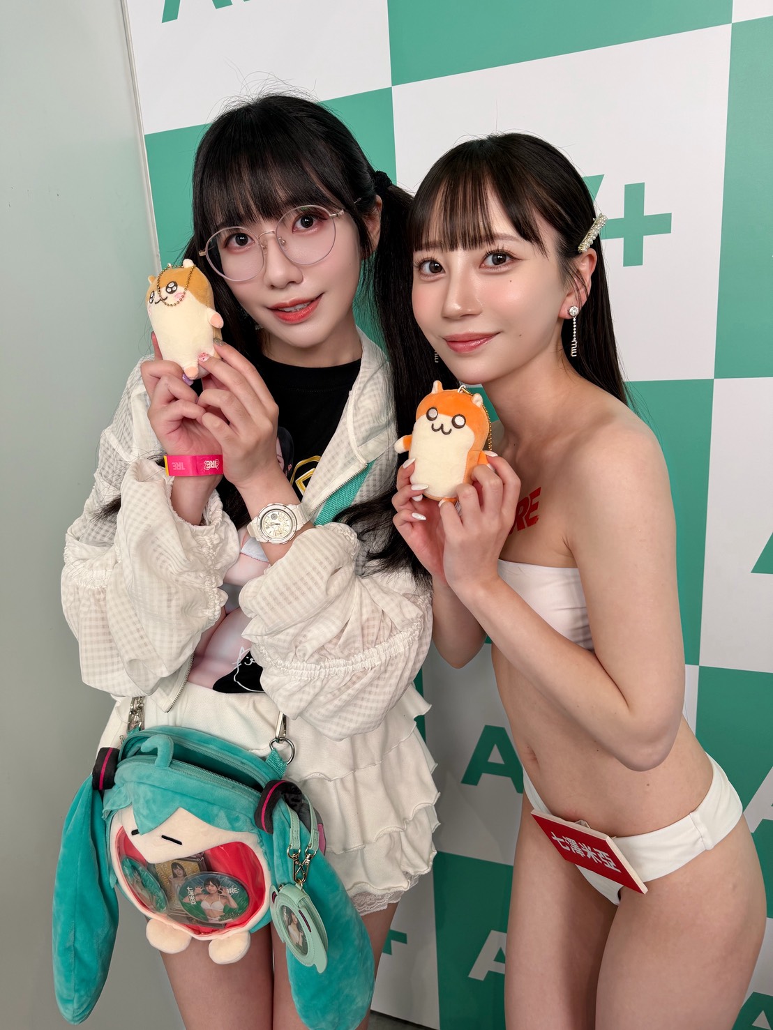 Lulumi 與七澤米亞（Mia Moodyz）TRE 活動合照，手拿可愛吊飾與初音未來痛包