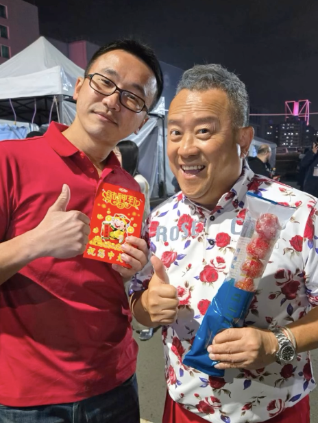 港星曾志偉手持甜一口草莓糖葫蘆，與吳章榮老闆對鏡頭展現招牌親切笑容
